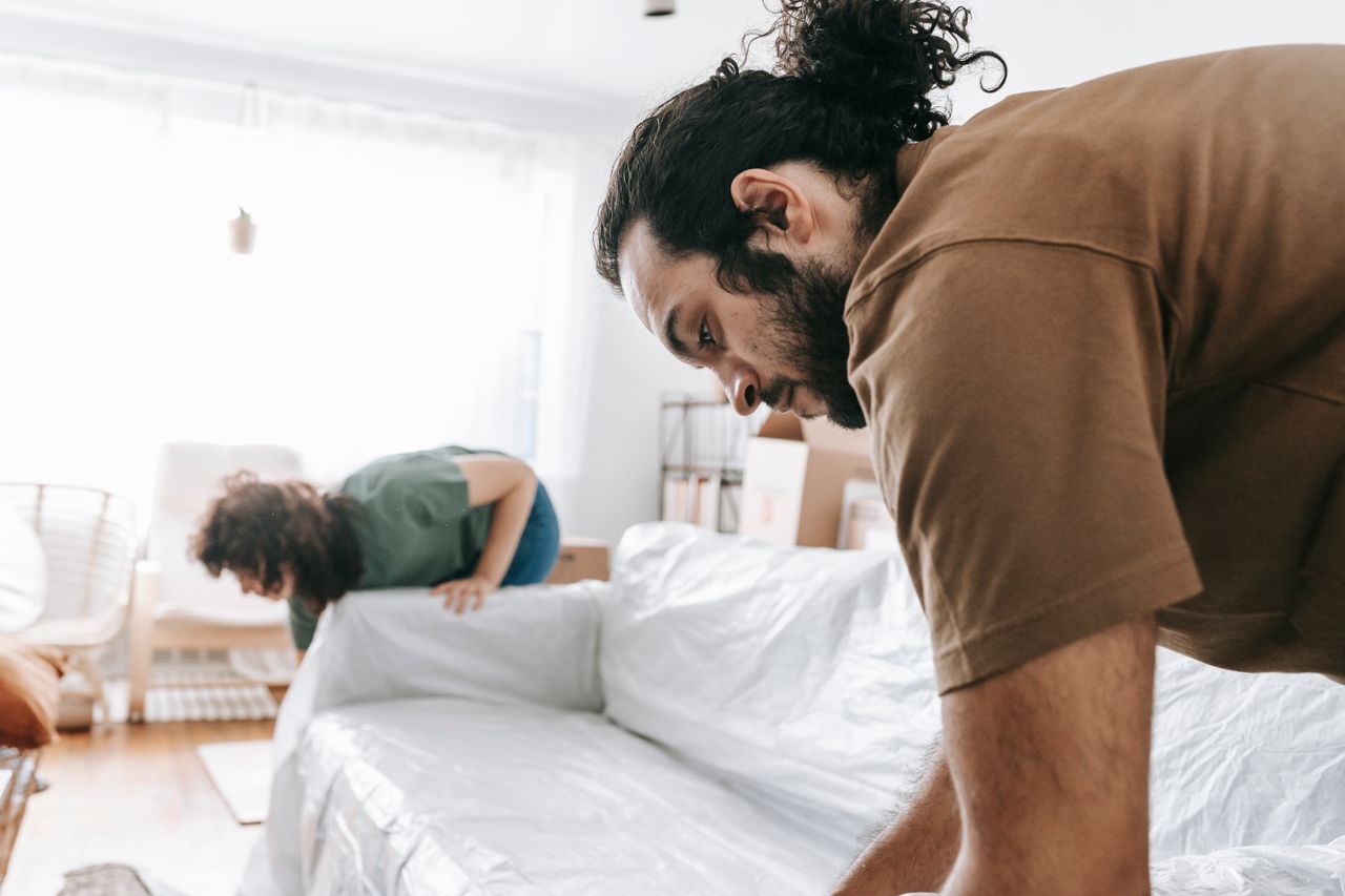 Un couple emballant des meubles dans un appartement lumineux, en train de préparer un déménagement.